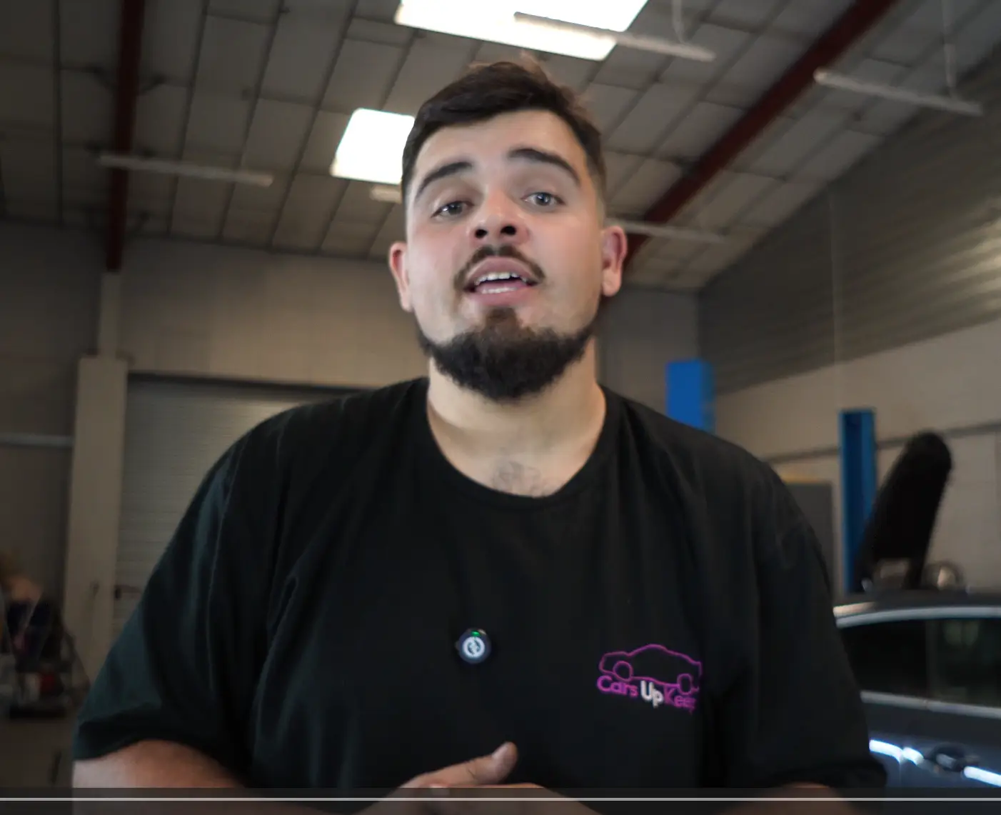 Mechanic working in a garage with a raised white car.